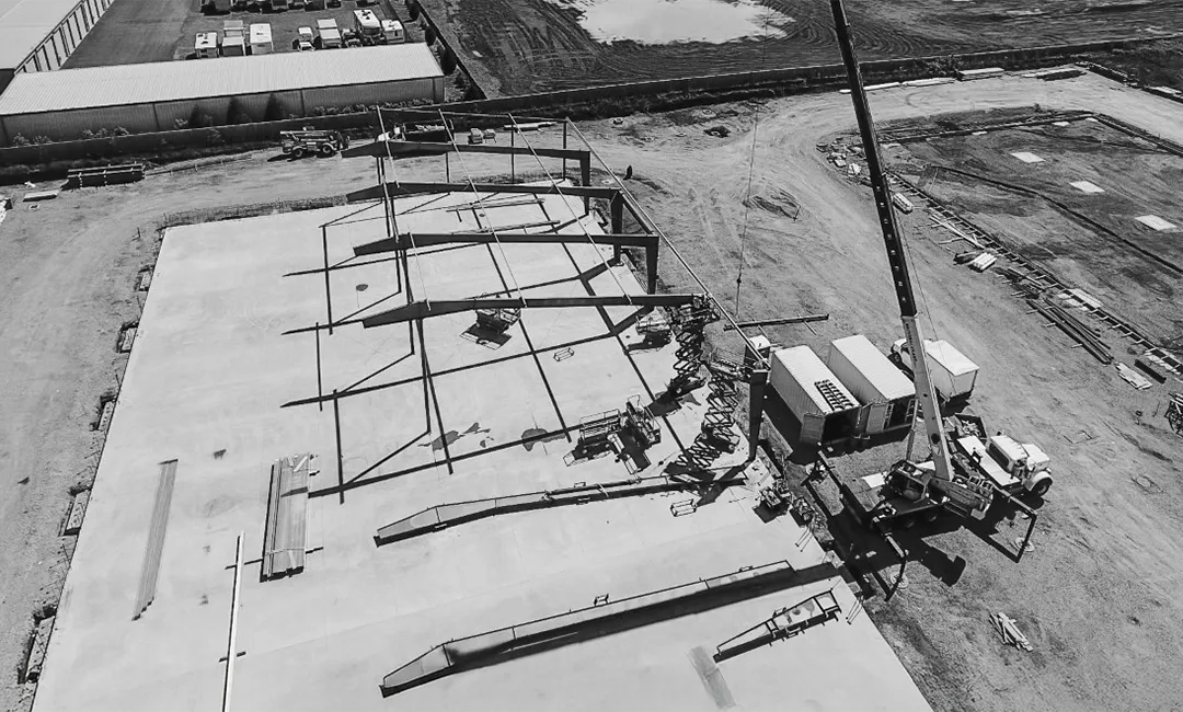 Black and white aerial view of a 55-ton crane and construction crew working on a large metal building project in Vancouver, Washington.