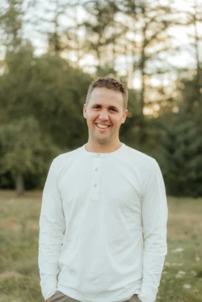 Wyatt posing for an outdoor professional headshot in Vancouver, WA, wearing a light-colored striped shirt.