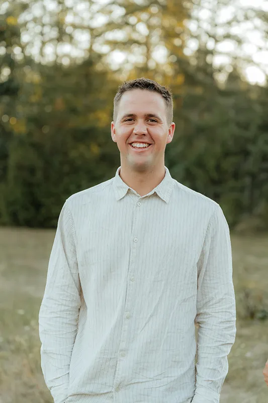 Wyatt posing for an outdoor professional headshot in Vancouver, WA, wearing a light-colored striped shirt.