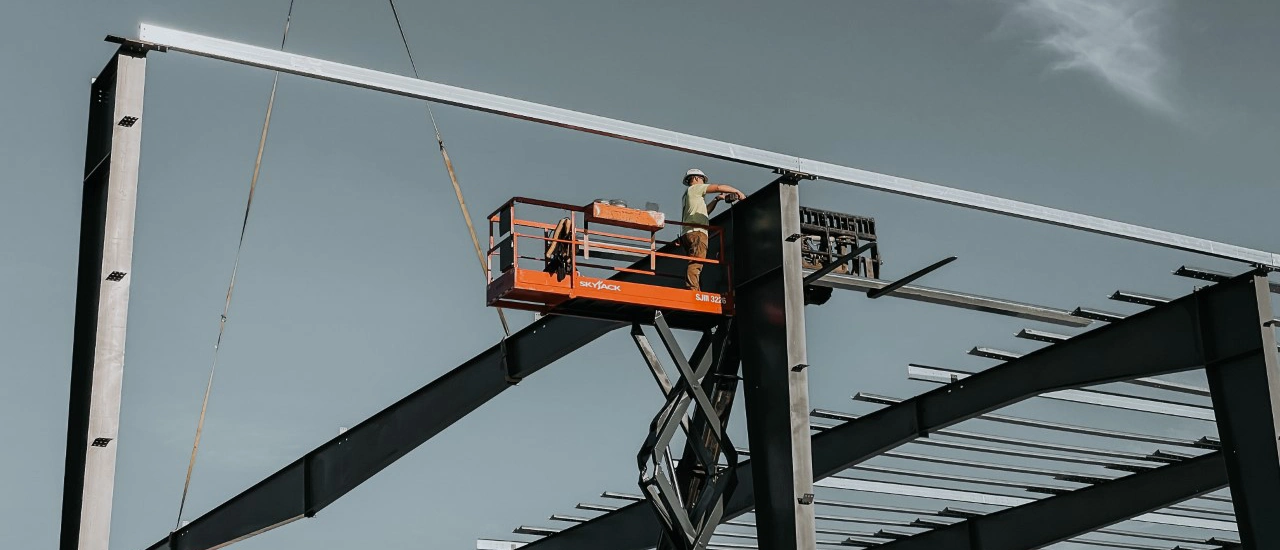 Westmore Construction worker on a scissor lift installing heavy-duty steel beams for a commercial building project in Vancouver, WA.