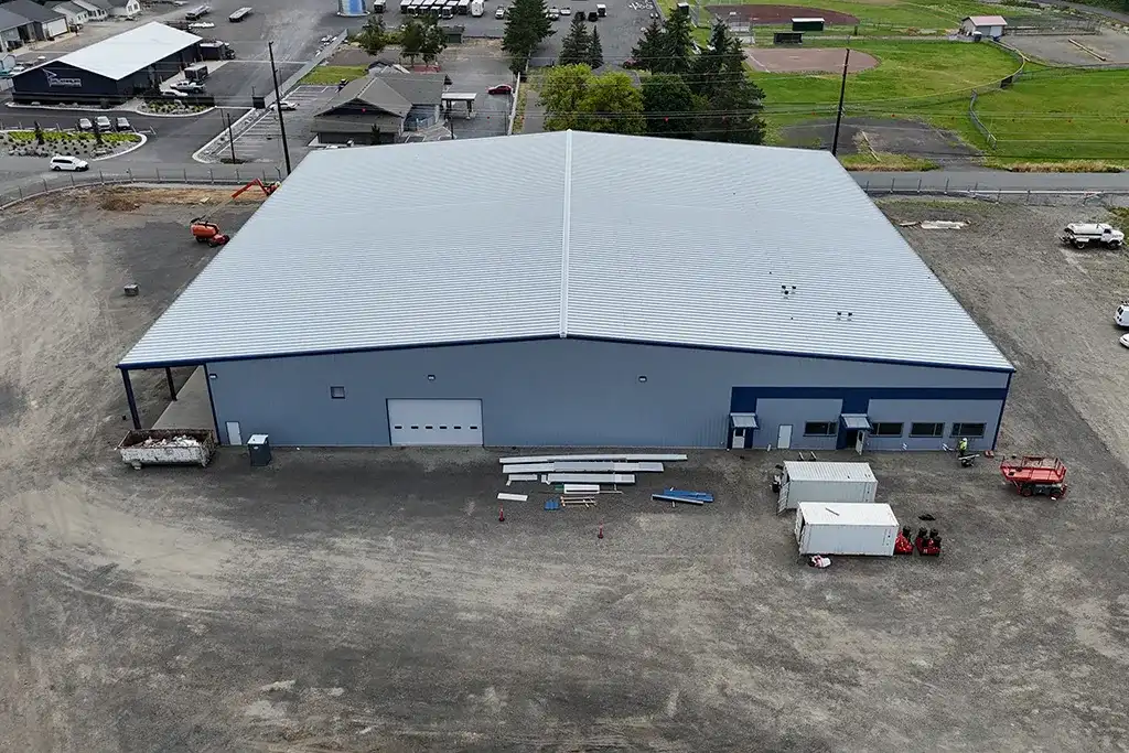 Overhead drone shot of a completed large-scale grey and blue metal warehouse building by Westmore Construction.