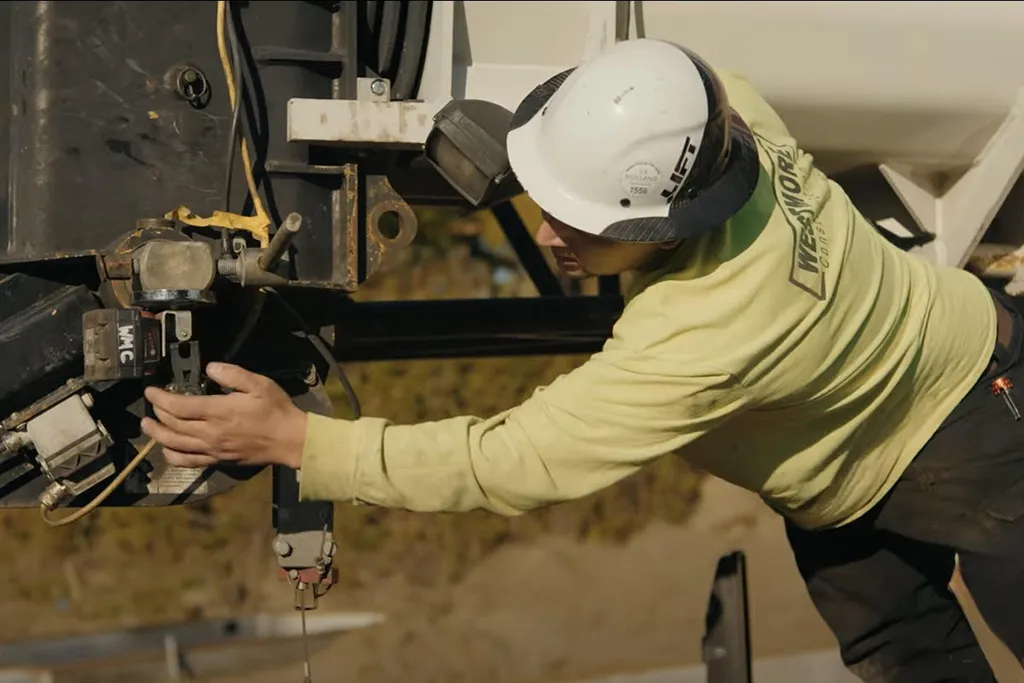 Close-up of a Westmore Construction professional in a hard hat inspecting heavy machinery at a Pacific Northwest job site.
