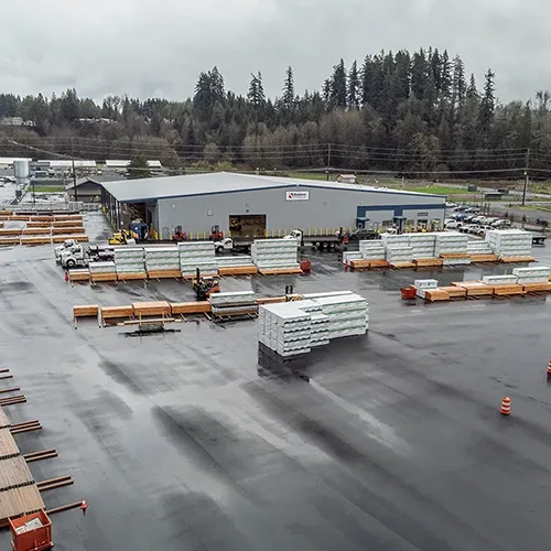 Aerial view of a large Westmore Construction industrial lumber yard and distribution facility in Vancouver, WA, featuring organized building materials.
