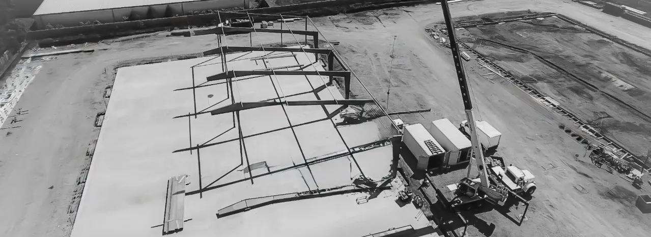 Black and white aerial view of a 55-ton crane and construction crew working on a large metal building project in Vancouver, Washington.