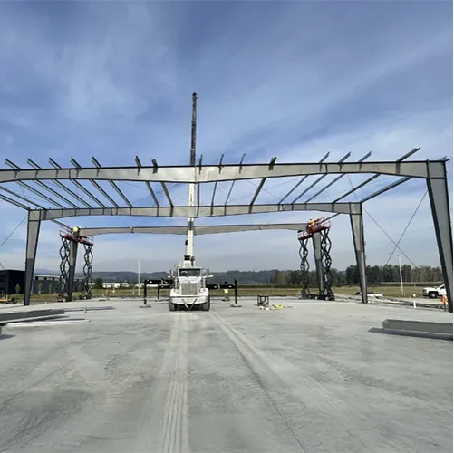 Large-scale commercial steel building frame under construction by Westmore Construction in Vancouver, WA, featuring a crane-assisted rafters installation on a concrete foundation.