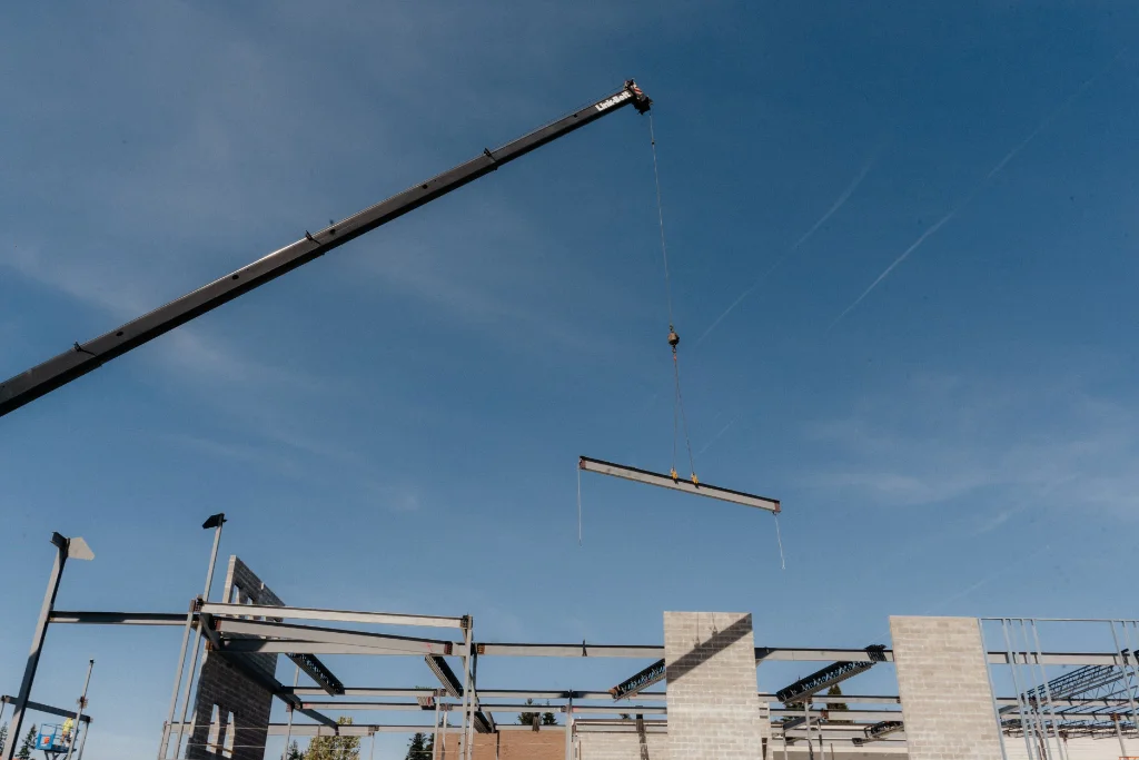 Professional crane services by Westmore Construction hoisting a steel beam during the industrial building erection phase in Portland, OR.