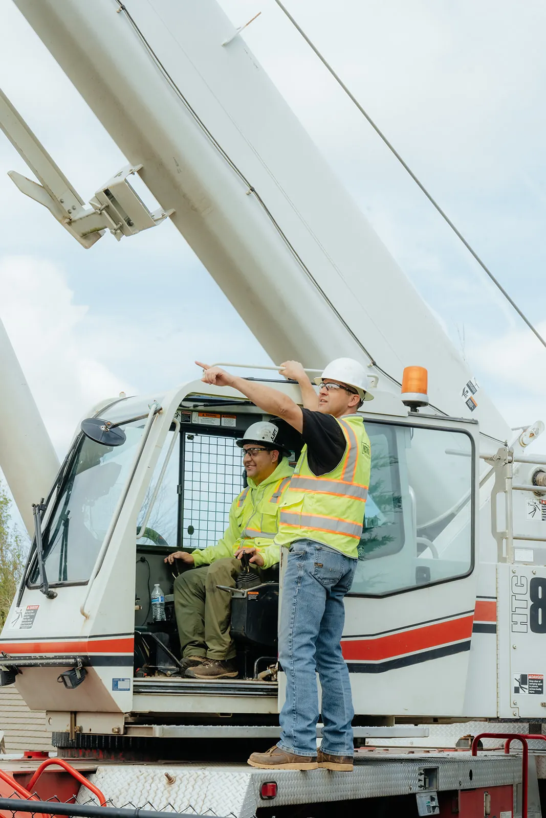 Westmore crew member at the crane cab, pointing toward the load during a lift