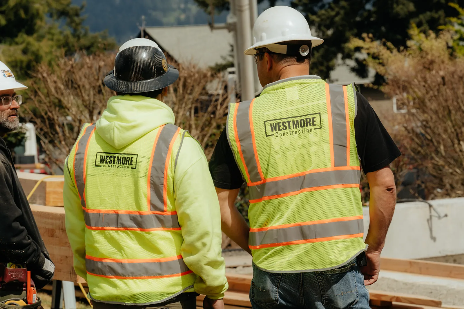 Two Westmore crew members in branded vests walking toward a residential timber-frame job