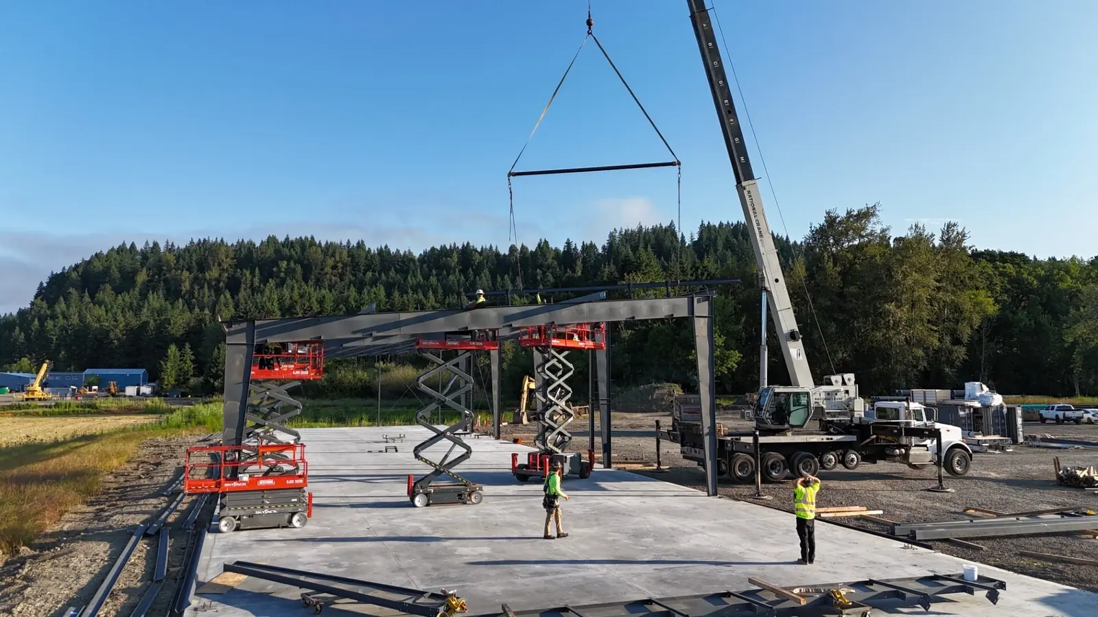 Westmore crane with a spreader bar setting a beam onto a steel building frame