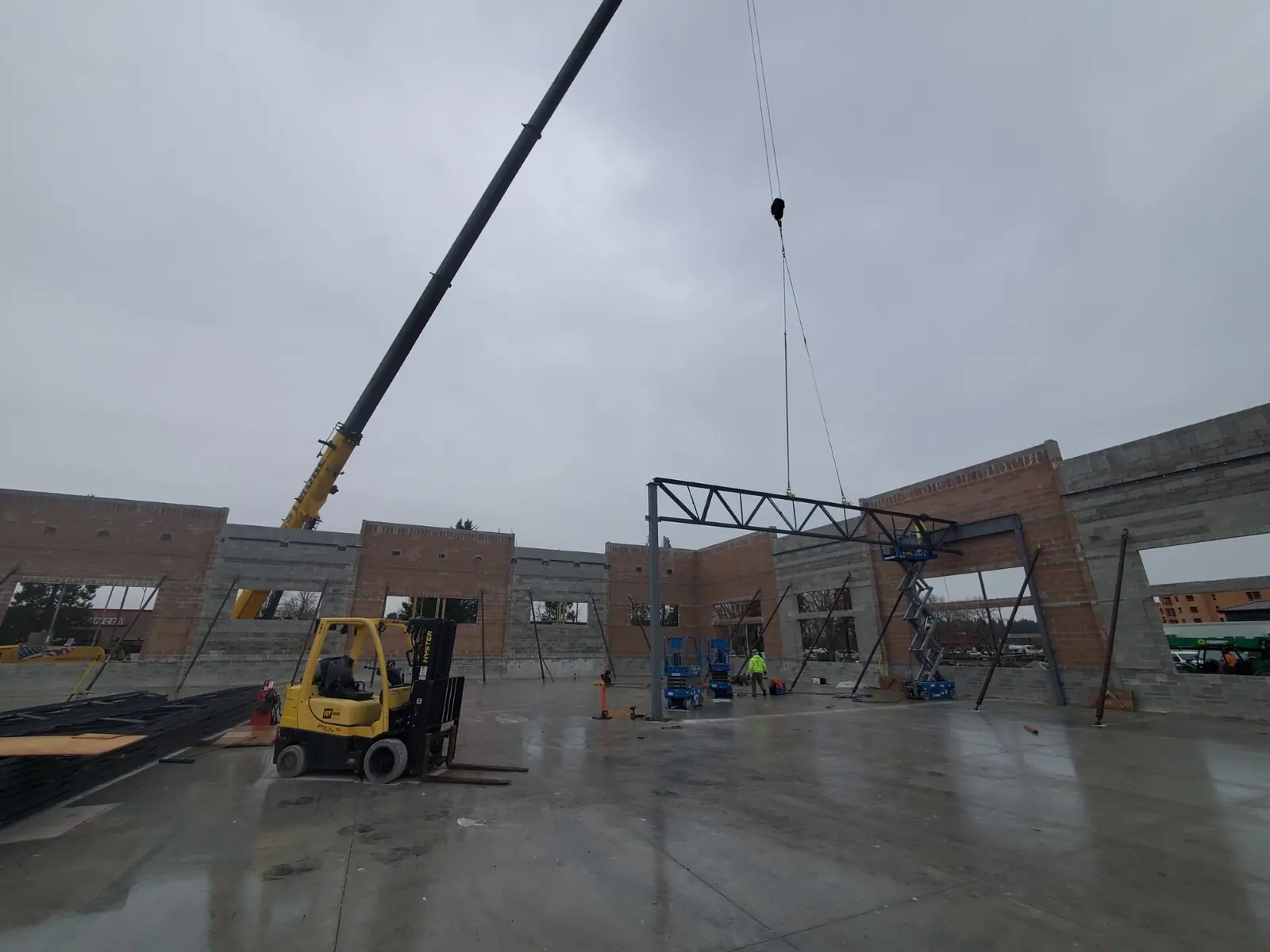 Westmore Grove crane setting a steel truss between block walls on a commercial jobsite