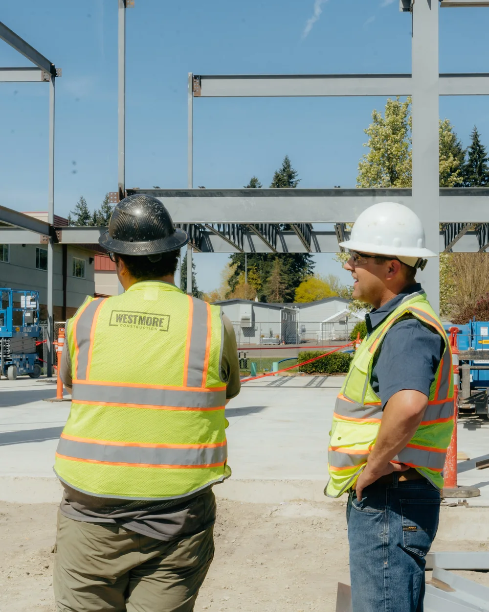Two Westmore crew members in safety vests at a structural steel frame